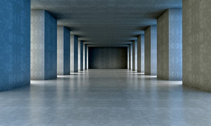 A long hallway with pillars and concrete floors.